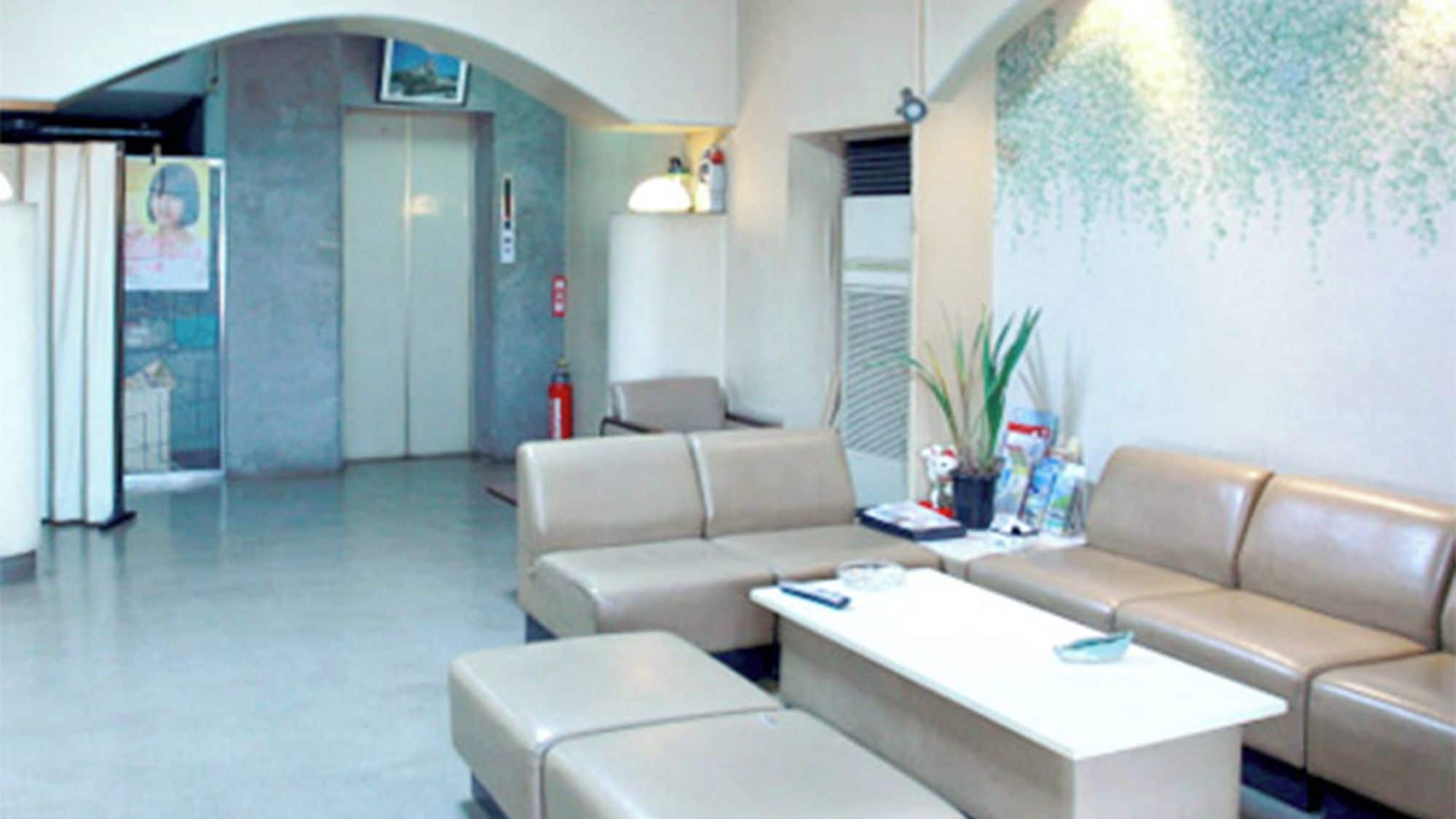 Un vestíbulo con mostrador de recepción, un sofá, una mesa de centro y una planta en la pared.