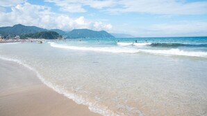 Una playa con aguas cristalinas, una orilla arenosa y montañas al fondo.