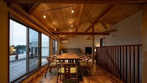 Una habitación amplia con una mesa de madera y sillas, ventanas grandes y un balcón.
