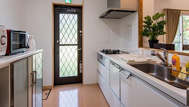 A compact kitchen with a microwave, stove, and sink. - United Resort Kibogaoka (Onna)