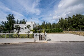 A gated entrance to a modern building with a flat roof and satellite dish.