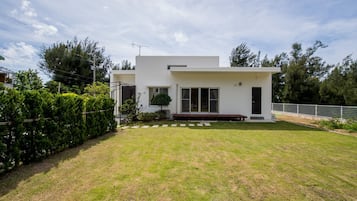 A modern two-story house with a flat roof, a front porch, and a well-maintained lawn.