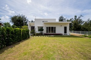 Una casa moderna de dos pisos con techo plano, un porche delantero y un césped bien cuidado.