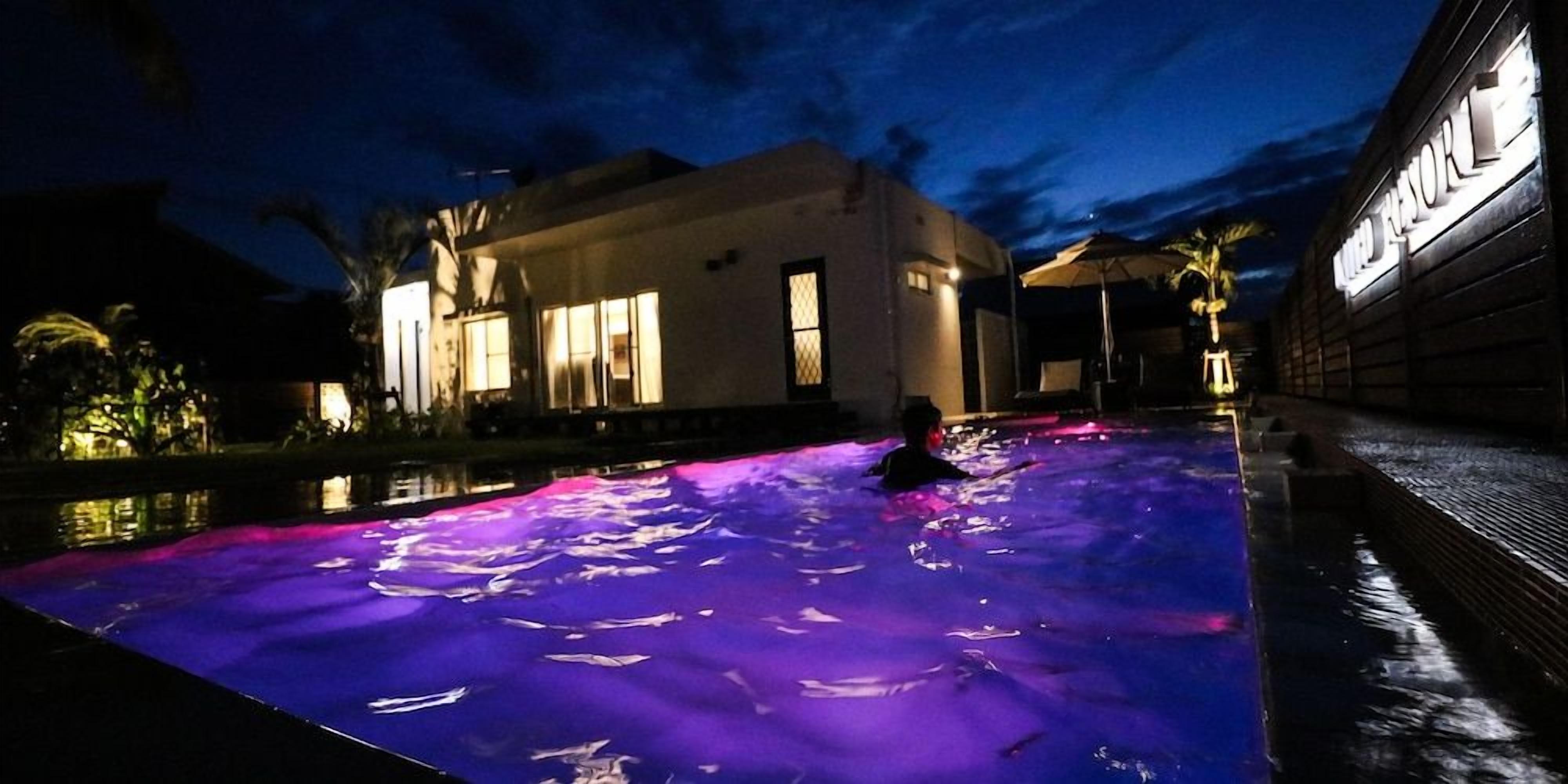 Una piscina con una persona, rodeada por un edificio con ventanas iluminadas.