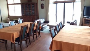 Un comedor con una mesa grande y sillas, un sofá, un armario y un televisor.