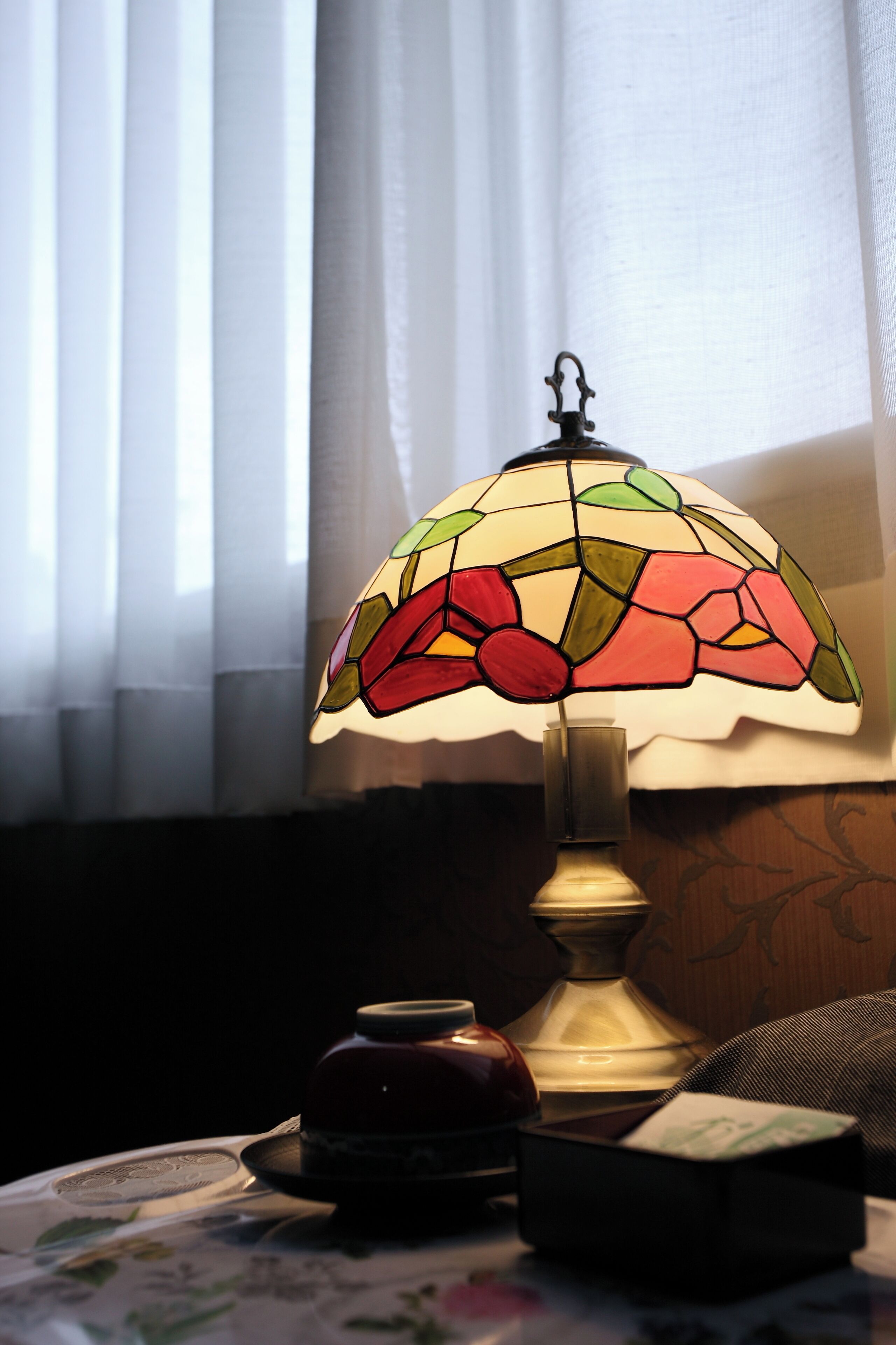 A table with a stained glass lamp, a small vase, and a box.