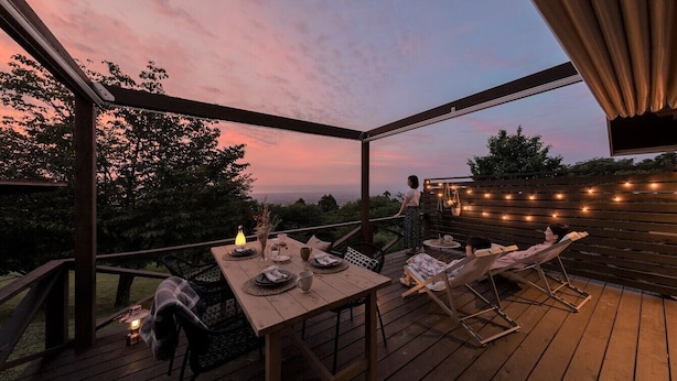 An outdoor deck with a table set for dining, chairs, and string lights. - Etowa Kasama (Kasama)