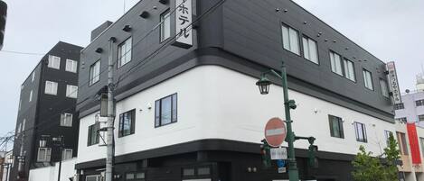 Un edificio de varios pisos con fachada blanco y negro, entrada visible y un cartel de prohibido el acceso.