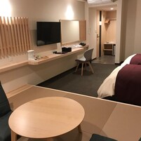 Una habitación de hotel con una cama, un escritorio, una silla, un televisor y una mesita.