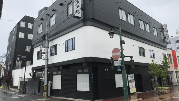 A multi-story building with a black and white facade, featuring a large window on the ground floor and several smaller windows on the upper floors. - Aizu Tsuruya Hotel (Aizuwakamatsu)