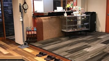 A shoe store interior with wooden flooring, a shoe display counter, and a clock on the wall.
