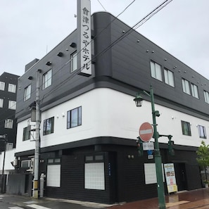 A building with a white and black facade, a no entry sign, and a street lamp. - Aizu Tsuruya Hotel (Aizuwakamatsu)