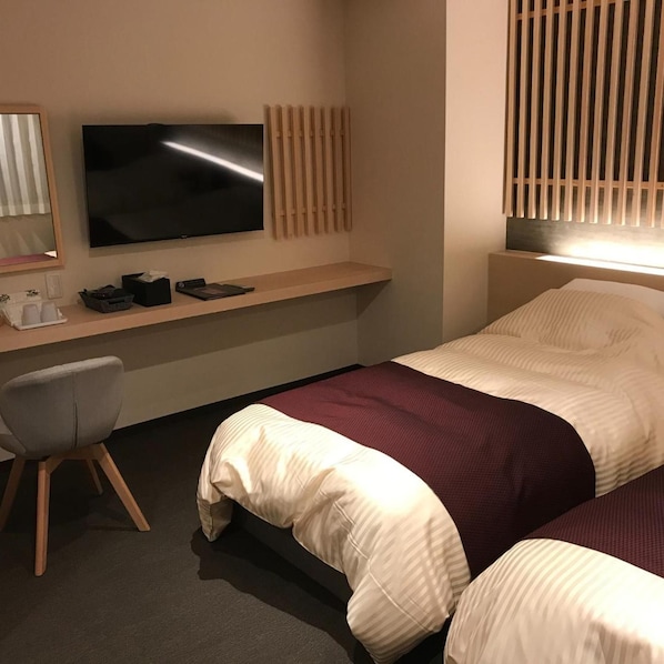 A hotel room with a bed, a desk with a flat-screen TV, a chair, and a window with blinds. - Aizu Tsuruya Hotel (Aizuwakamatsu)
