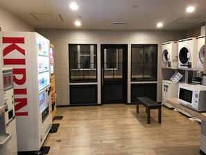 A laundry facility with a vending machine, washing machines, and dryers. - Aizu Tsuruya Hotel (Aizuwakamatsu)