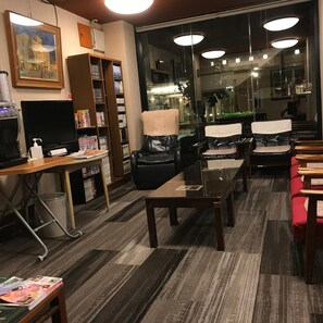 A hotel room with a large window, a desk with a computer, a bookshelf, and a seating area with chairs. - Aizu Tsuruya Hotel (Aizuwakamatsu)