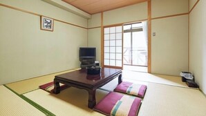 A traditional Japanese room with tatami flooring, a low wooden table, a television, and sliding doors leading to a balcony. - Niimi Chiya Onsen Ibuki no Sato (Niimi)