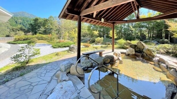 A covered outdoor area with a stone pathway, a small pond, and surrounding greenery. - Niimi Chiya Onsen Ibuki no Sato (Niimi)