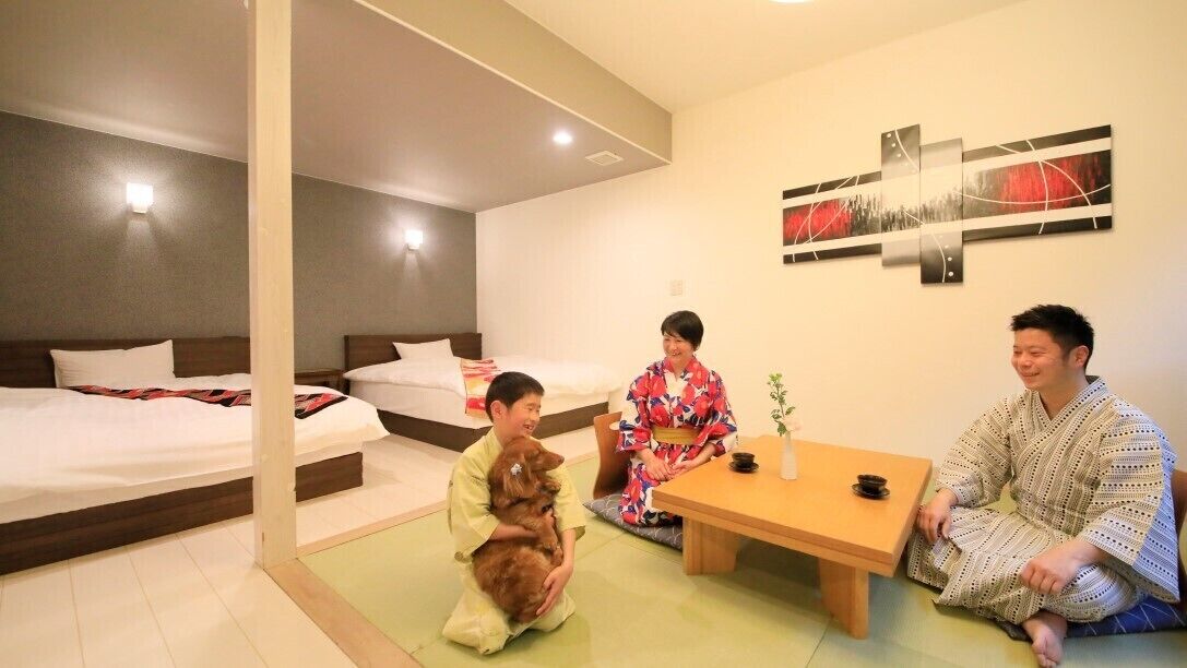 A hotel room with two beds, a small table, and a wall-mounted artwork.