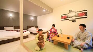 A hotel room with two beds, a small table, and a wall-mounted artwork.