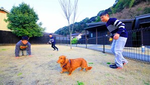 A fenced outdoor area with a sandy ground, a dog, and three people. - Beppu Onsen Wanko no Yado Yururi (Beppu)
