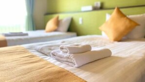 Ett hotellrum med två sängar, båda med vita lakan och kuddar, en grön vägg och ett fönster med gardiner.