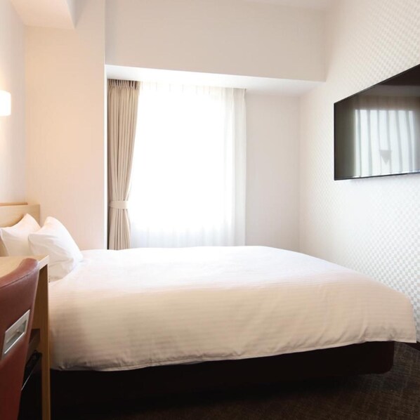 Een hotelkamer met een bed, een bureau en een televisie aan de muur.