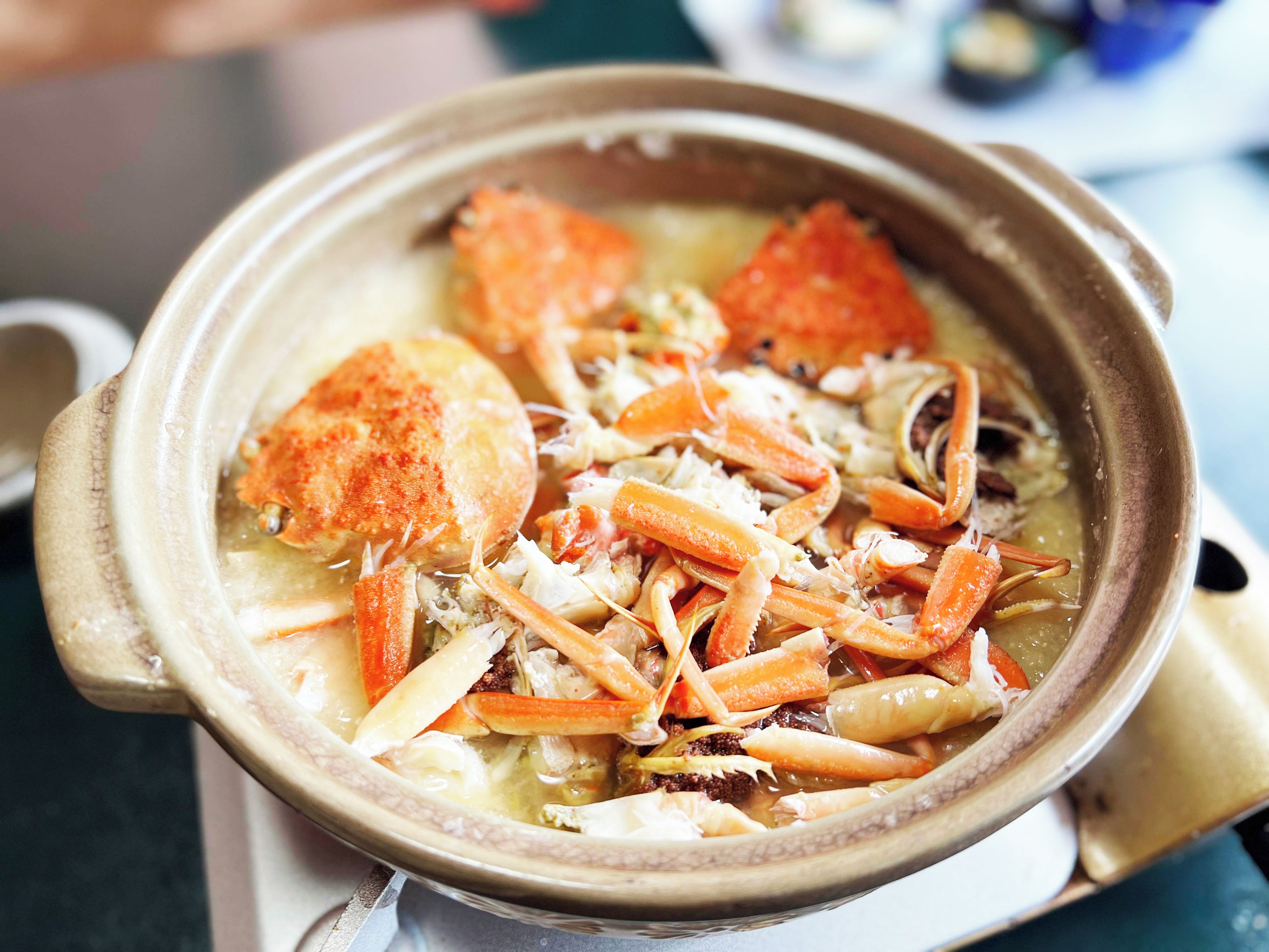 A bowl of seafood soup with crab legs and vegetables.