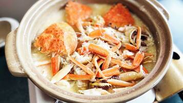 A bowl of seafood soup with crab legs and vegetables.