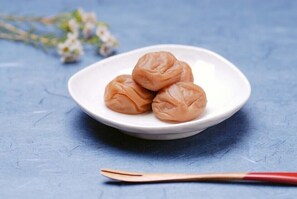 A white plate with three round, brown pastries on a blue surface. - The Hotel Teramoto (Tanabe)