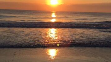Un coucher de soleil sur une plage, avec des vagues.