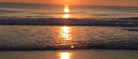Atardecer sobre una playa con olas.