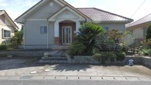 A single-story house with a tiled roof, a front porch, and a small garden with various plants. - Smith no Ie Chosei (Chosei)