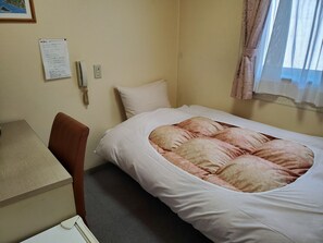 A hotel room with a bed, a desk, a chair, a wall-mounted phone, and a window with curtains. - Business Hotel Hosen An-nakakan (Annaka)