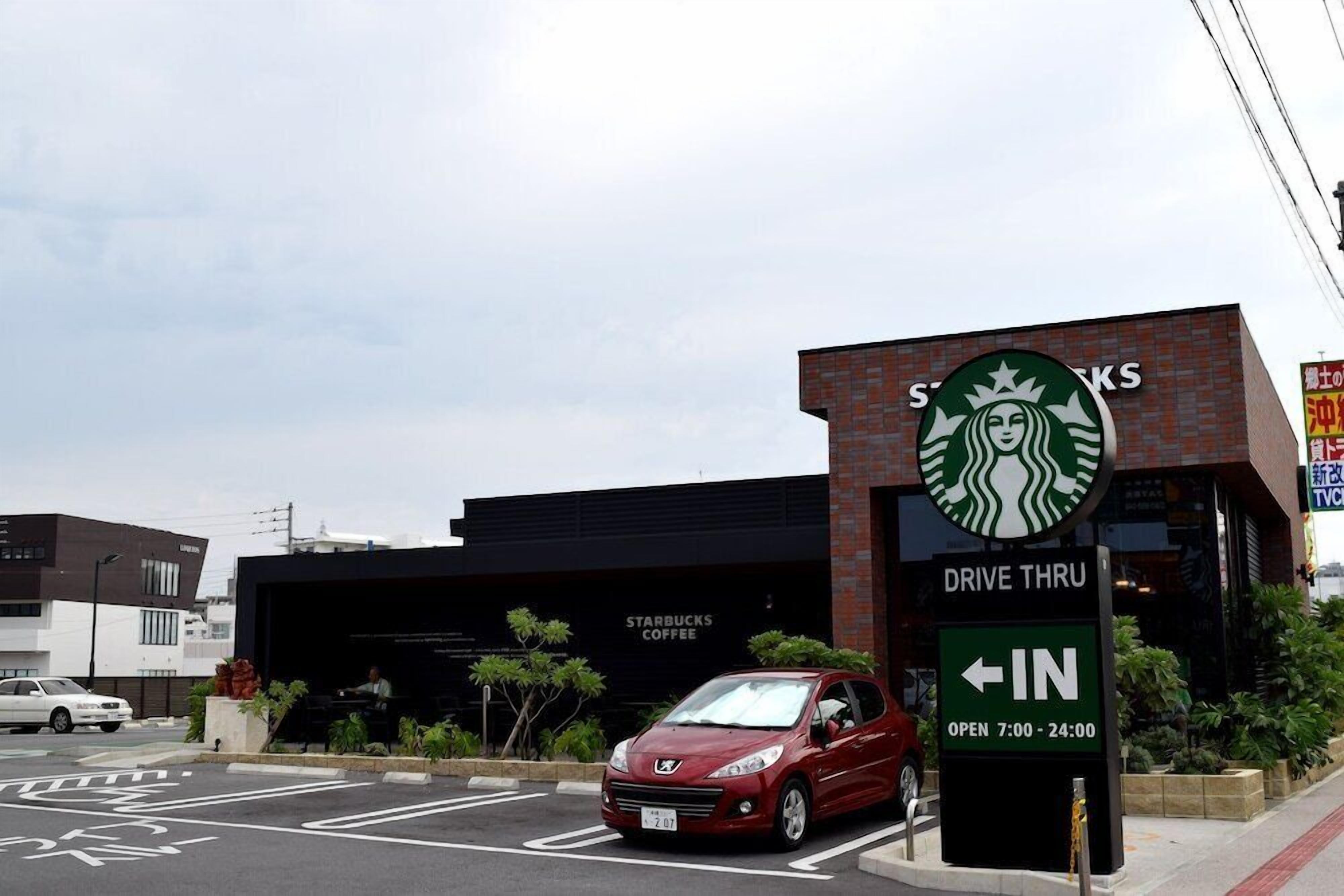 A Starbucks drive-thru with a red car parked in the lot.