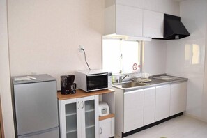 A compact kitchenette with a microwave, coffee maker, and a small refrigerator. - Rainbow Terrace (Ginowan)