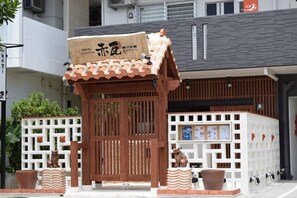 A traditional Japanese-style entrance with a wooden gate, a small pavilion, and a white fence with decorative elements. - Rainbow Terrace (Ginowan)