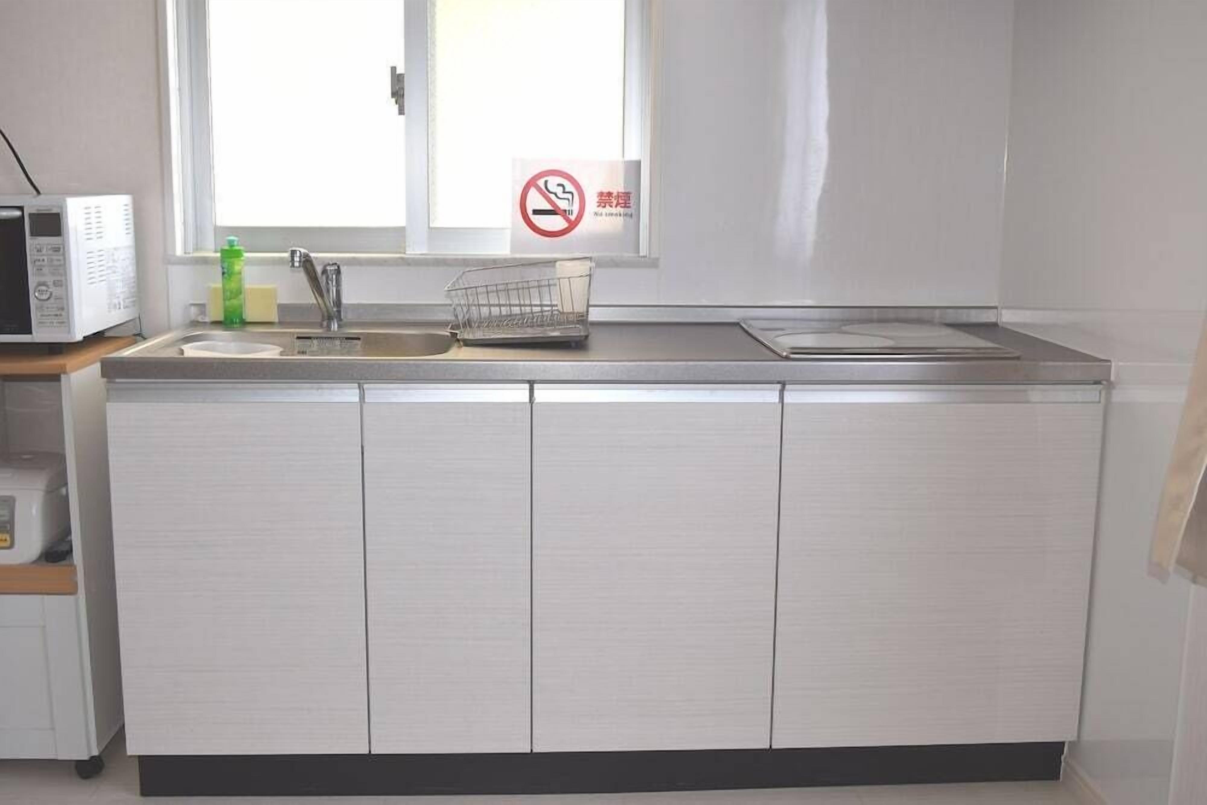 A kitchen with a microwave, sink, and a no-smoking sign.