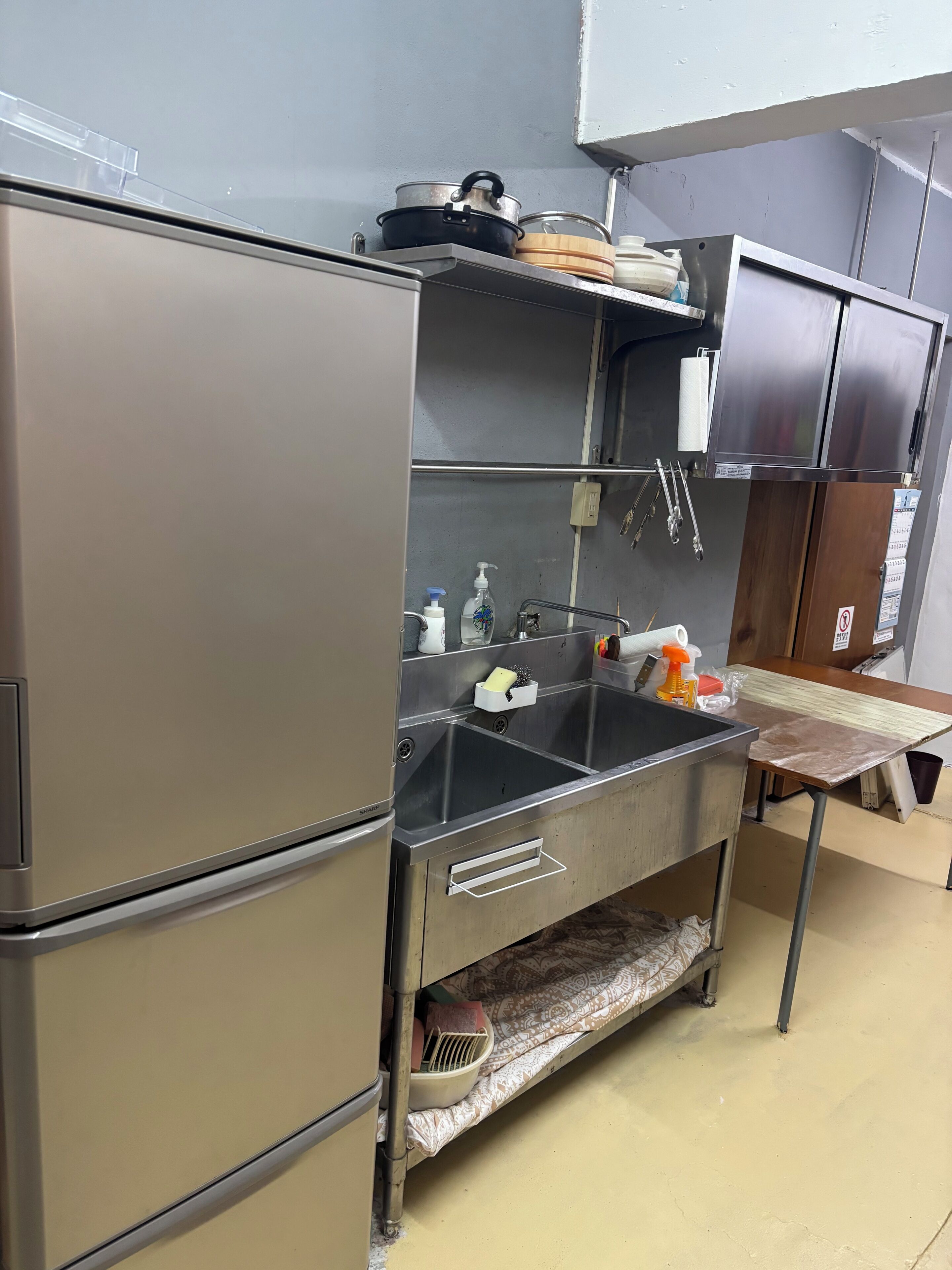 Een kleine keuken met roestvrijstalen apparatuur, een spoelbak en een aanrecht met diverse spullen.