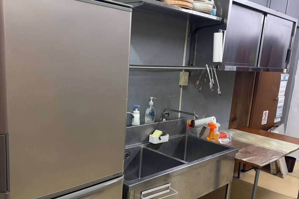 A compact kitchen with stainless steel appliances, a sink, and a countertop with various items.