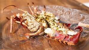 Een kreeft op een glazen bord met een houten achtergrond.