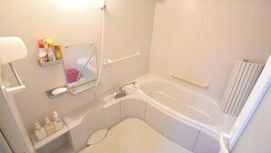 Een compacte, moderne badkamer met een bad, toilet, wastafel en spiegel.