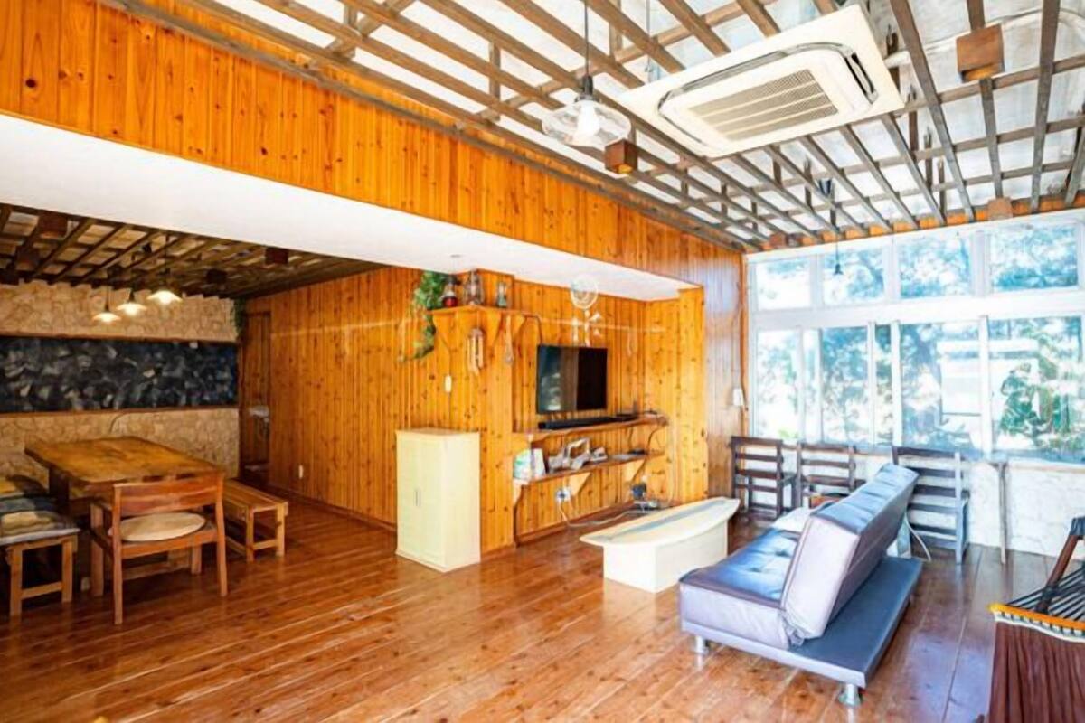 A wooden interior with a stone wall, wooden furniture, a sofa, and a television.