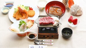 A dining setup with various dishes, including tempura, sashimi, and grilled meat, along with condiments and utensils. - Pension Mangame (Awaji)