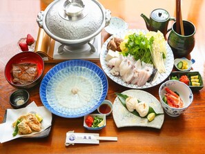 A traditional Japanese meal setup with various dishes, including sushi, sashimi, and a hot pot. - Pension Mangame (Awaji)