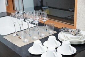 A table set with wine glasses, water glasses, and white cups on a black tablecloth. - Villa de Fleur Secret Villas (Motobu)