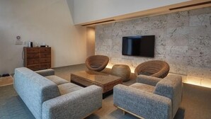 Ein modernes Wohnzimmer mit Steinwand, Flachbildfernseher und Holzschrank.