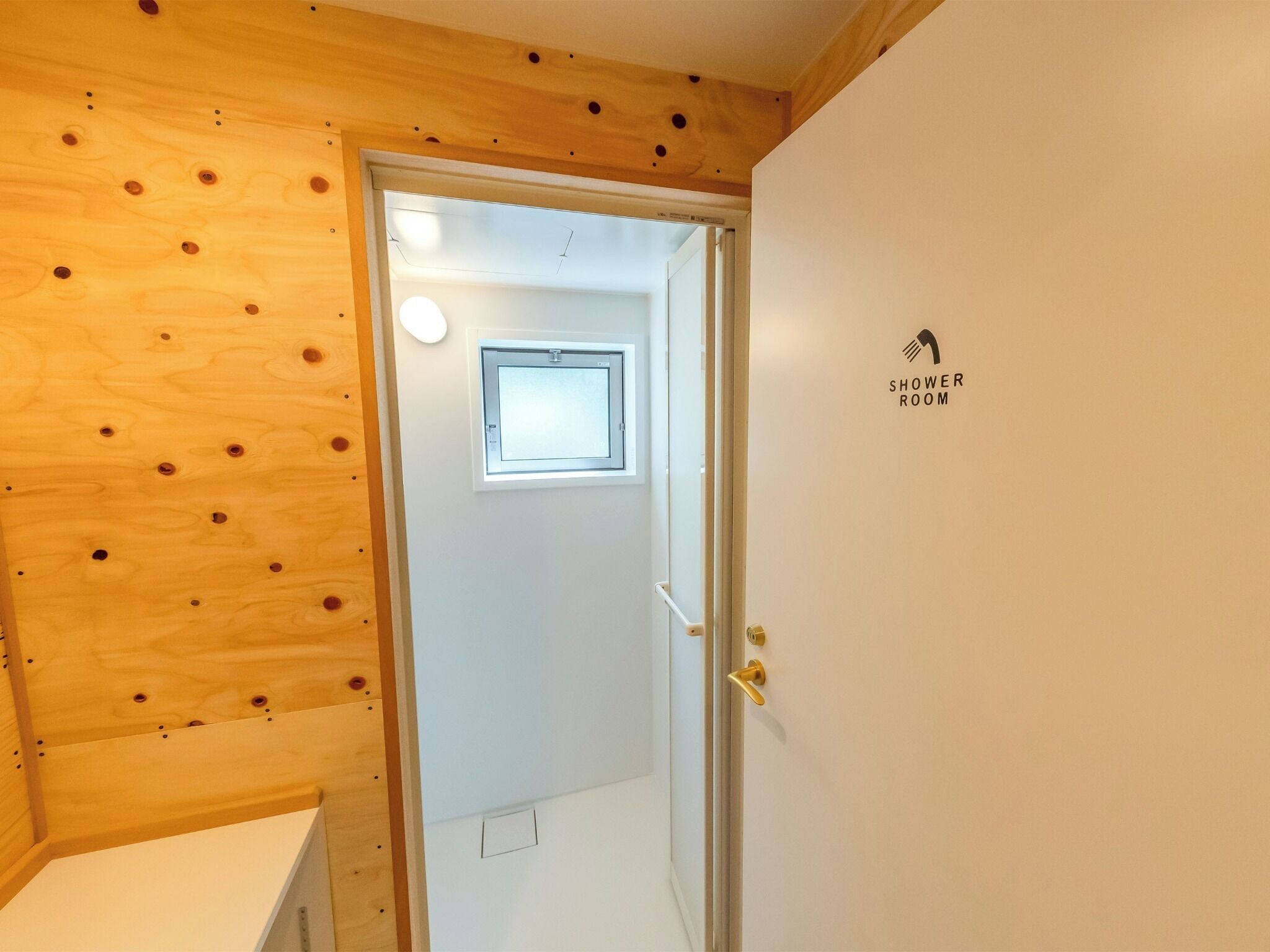 A wooden-paneled room with a door leading to a shower room.