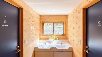 Un baño pequeño y con acabados de madera, con dos lavamanos y una ventana.