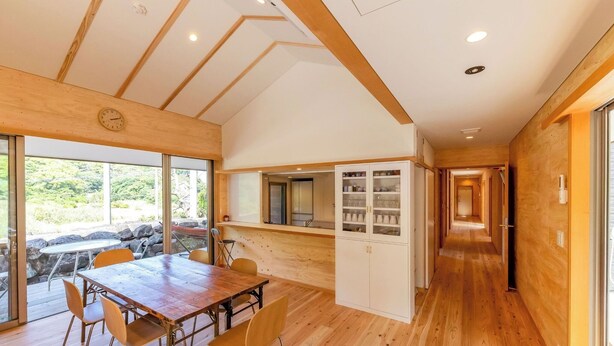 Un interior moderno con una mesa de comedor de madera, sillas y una cocina con armarios.