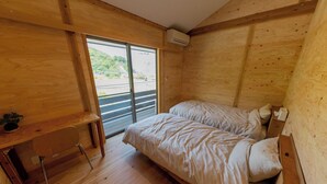 Una habitación de cabaña de madera con una cama, un escritorio pequeño y una ventana.